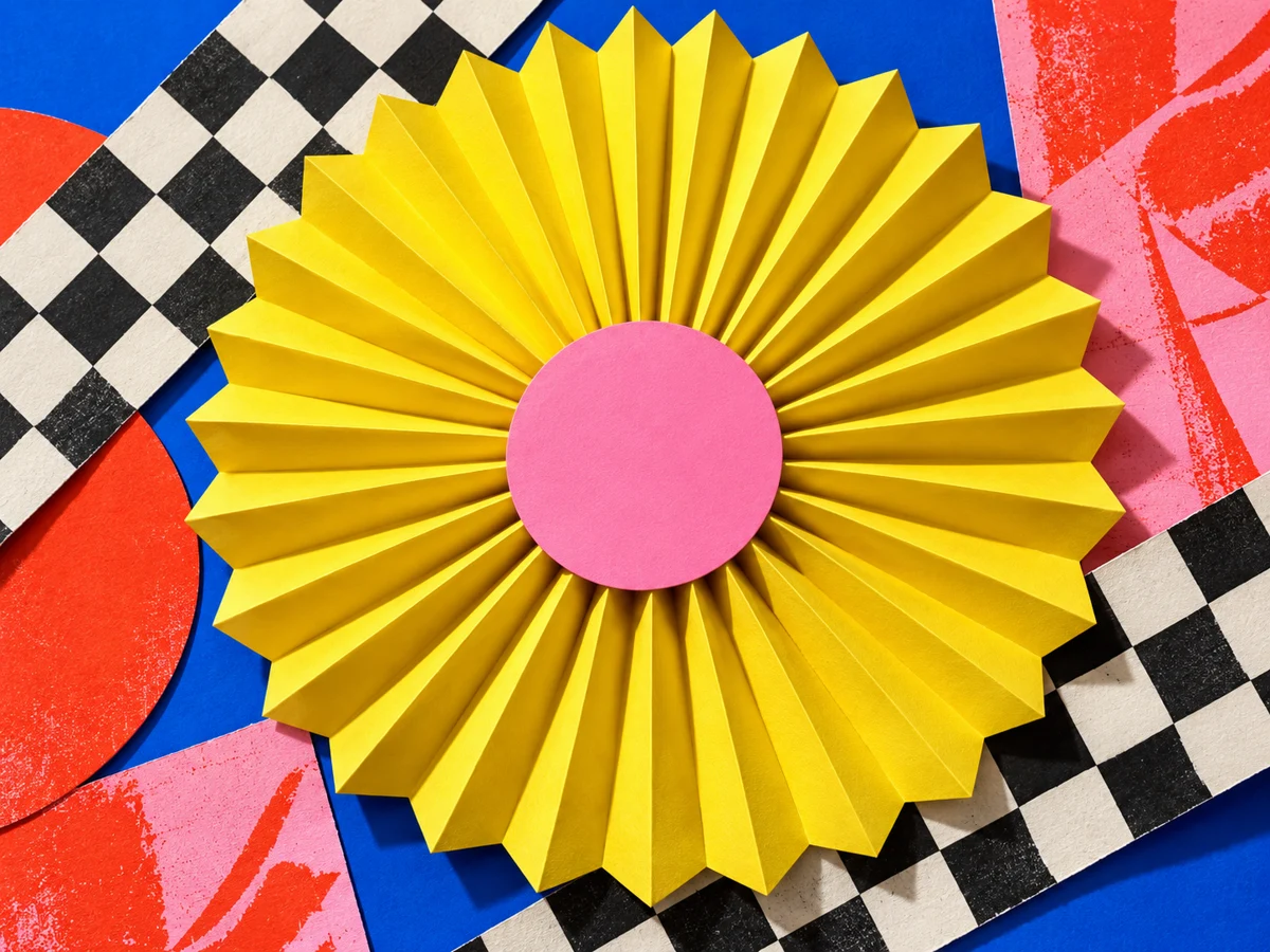 Acid-yellow paper rosette with a pink center, layered over cobalt, checkerboard, and bright screenprinted paper.